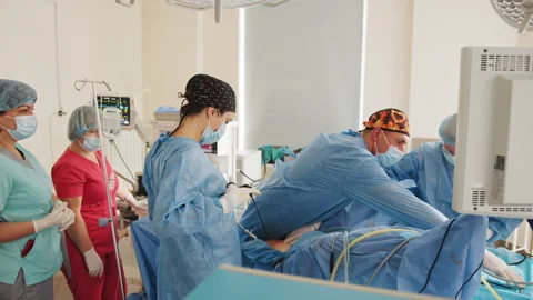 Cooperating of doctors and surgeons processing surgical operation in operating Stock Footage 174183023