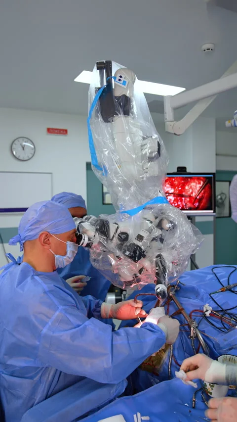 Cooperative surgeons look at microscope carrying out surgery. Stock Footage 297298665