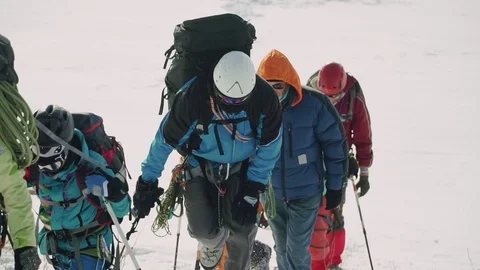 Coordinated team of climbers climb up the mountain in deep snow fatigue Stock Footage 105865448