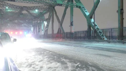 Cop car driving with strobe lights ON during snow storm on paralyzed bridge Video stock 103703871