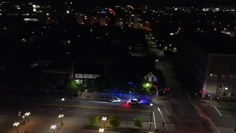 Cop car night time traffic stop in otherwise tranquile city 4K Stock Footage 324832486