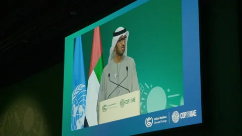 COP28, Dubai: A large screen broadcasts Sultan al-Jaber's speech Stock Footage 289730049
