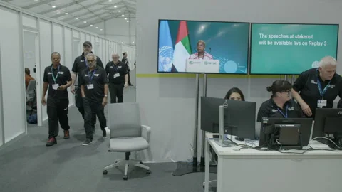 COP28, Dubai: Staff working on computers, others walking down a corridor Stock Footage 289727728