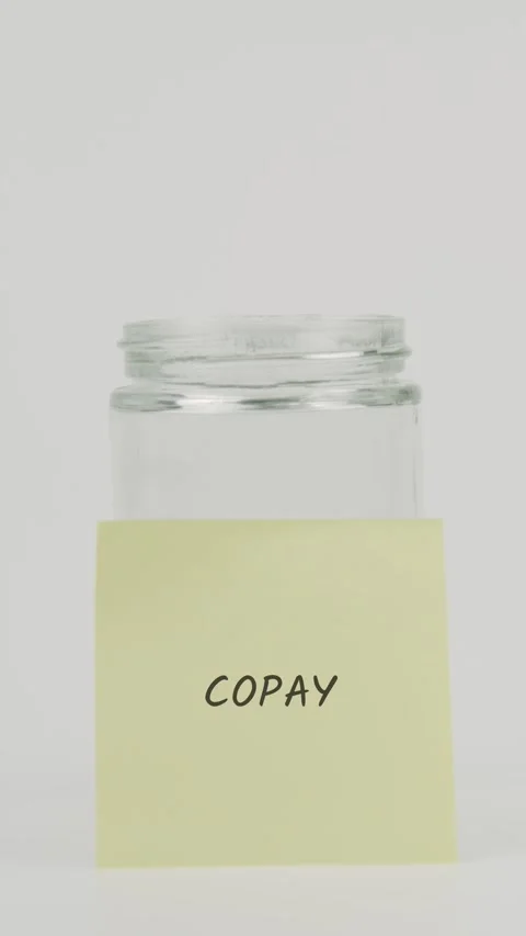 Copay text or word on yellow sticky note attached to glass jar with hand Stock Footage 311699740