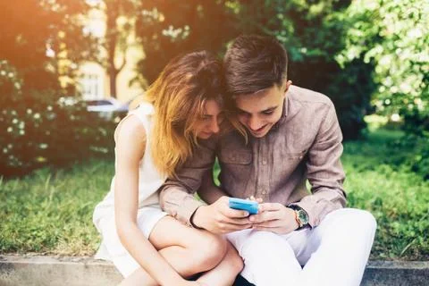 Cople using a smartphone, sitting in the park Stock Photos