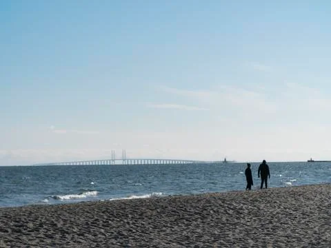 Cople walking on the beach on a cold but clear day, with waves in the water and  Stock-Fotos