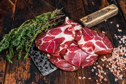 Coppa, Capocollo, Capicollo Cured ham on meat cleaver. Dark wooden background Stock Photos