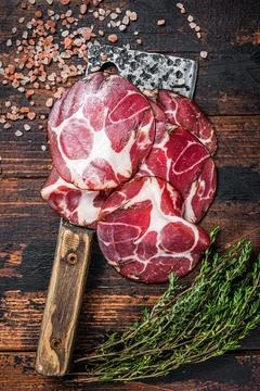 Coppa, Capocollo, Capicollo Cured ham on meat cleaver. Dark wooden background Stock Photos