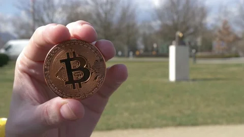 Copper bitcoing token with Satoshi Nakamoto statue in the background 스톡 동영상 235674749