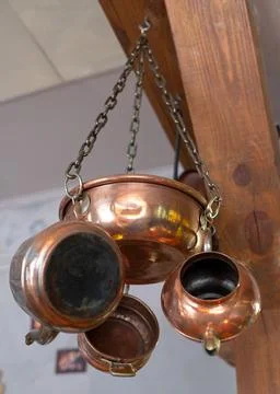 Copper dishes - pots, kettle and bowl hang on the wall. Stock Photos