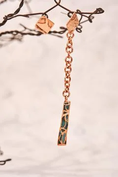 Copper earrings in the shape of an asymmetrical triangular chain, handmade on Foto stock
