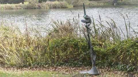 Copper frog on a reed by the side of the lake Stock Photos