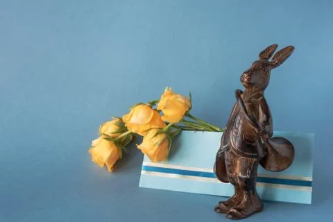 Copper hare-postman with postal horn and envelope with yellow roses Stock Photos