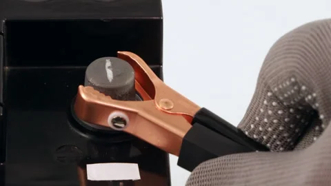 Copper jumper cable clamp being connected to a car battery terminal Stock Footage 321414974