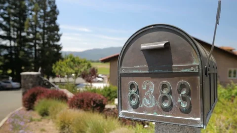Copper metal mailbox with stone base by house. Mail flag up A Stock Footage 110878889