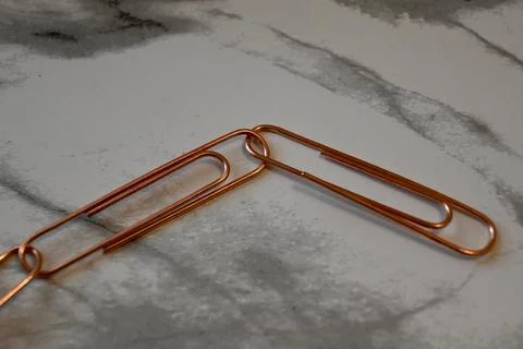 Copper paper clips on marble surface Stockfoto's