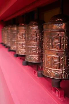 The copper prayer wheels on the bright red facade of the monastery in Monjo.. Stock Photos