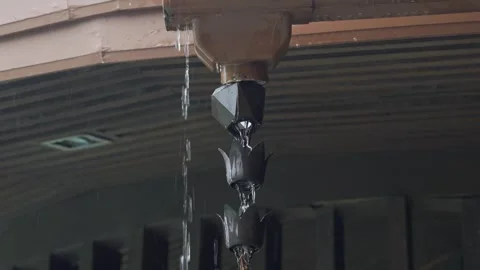 A copper rain chain with water flowing down from a roof gutter,Close-up of .. Stock Footage 335581468