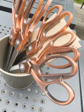 Copper tailoring scissors standing in container on table Stock Photos