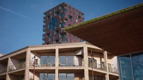 Copper-Toned Tower Rises Behind A Building With A Wooden Canopy Stock Footage 340894964