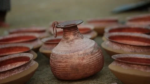 Copper water jug centered among rows of hammered bowls outdoors Nepal Stock Footage 342140559