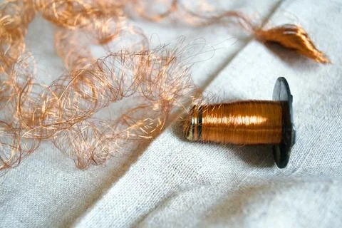 Copper wire spool with tangled metallic curls on linen fabric. Stock Photos