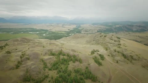 The copter flies high above the hilly desert area. Snowy mountains and rivers in Stock-Footage 278367189