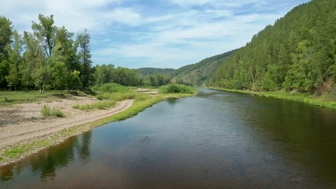 A copter flies low over the river toward the shore. Stock Footage 114880572