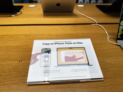 Copy on iPhone Paste on Mac instructional display on a wooden desk at a tec.. Stock Photos