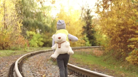 Copy paste. Back view of little lonely girl walking on railway with Teddy bear Stock Footage 128452969
