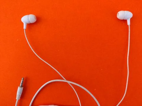 Copy space between two white ear buds isolated on orange background Stock Photos