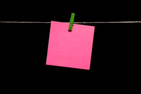 Copy space. Black background. A pink sheet of paper with a green clothespin Stock Photos