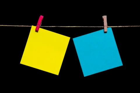 Copy space. Black background. Yellow and azure sheets of paper with clothespins Stock Photos