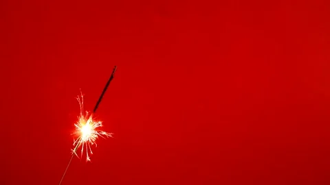 Copy space. Close up of Brightly burning sparkler on a red background with lots  Stock Footage 171424369