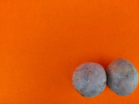 Copy space of orange background with two sapodilla or chikoo in corner. Stock Photos