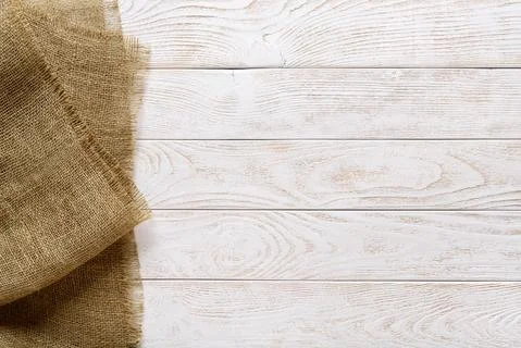 Copy space on a rustic wood tabletop painted white and burlap on a side. Stock Photos