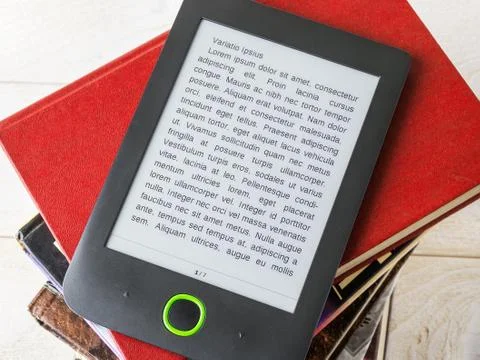 Copy space on a screen of e-book reader over a stack of ordinary paper books. Stock Photos