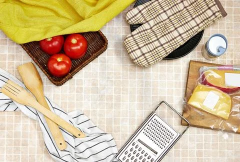 Copy space surrounded by cooking utensils and a blocks of cheese above wooden cu Stock Photos