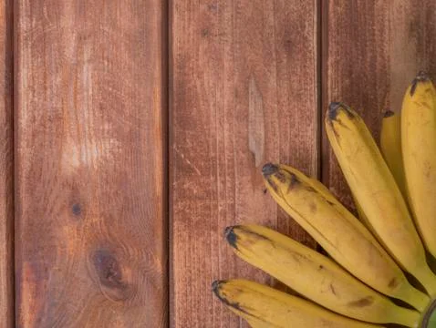 Copy space for text with mini small bananas on a wooden surface. Foto stock