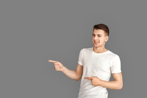 Copy Space for Text or Product. Young man standing isolated on grey pointing Stock Photos
