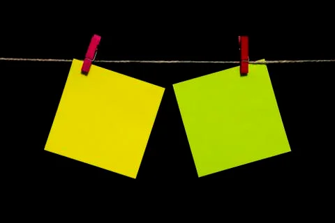 Copy space. Two yellow sheets of paper with red clothespins hang from a rope. Stock Photos