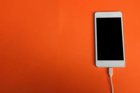 Copy space white Smartphone Plug In with Charger Adapter on orange Background Stock Photos