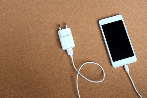 Copy space white Smartphone Plug In with Charger Adapter on brown Background Stock Photos