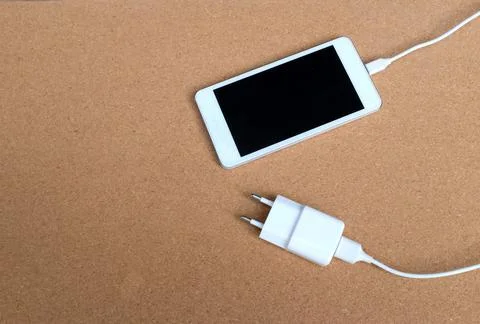 Copy space white Smartphone Plug In with Charger Adapter on brown Background Stock Photos
