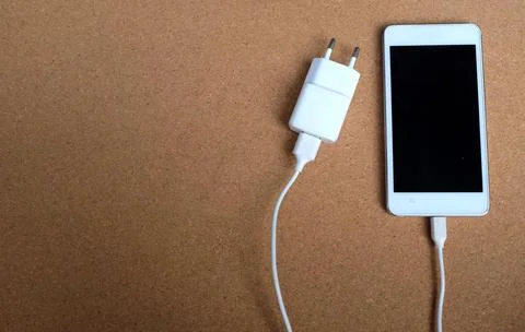 Copy space white Smartphone Plug In with Charger Adapter on brown Background Stock Photos