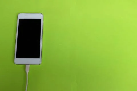 Copy space white Smartphone Plug In with Charger Adapter on green Background Stock Photos