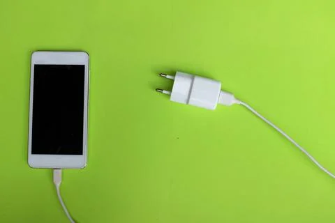 Copy space white Smartphone Plug In with Charger Adapter on green Background Stock Photos
