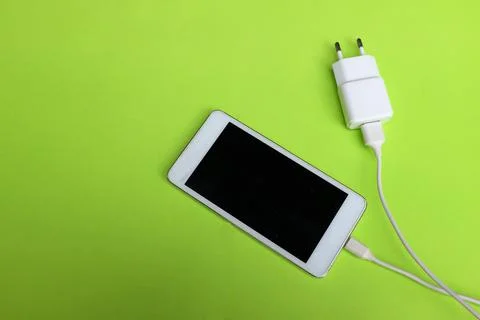 Copy space white Smartphone Plug In with Charger Adapter on green Background Stock Photos