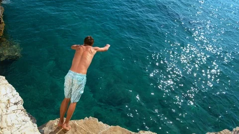 COPY SPACE: Young man on a summer vacation does cliff diving on a sunny day. Stock Footage 126838286