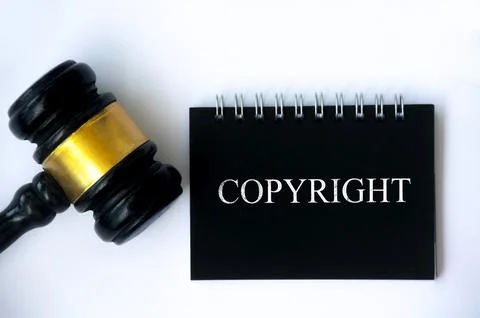 Copyright law text on black notepad and gavel on white background cover. Stock Photos